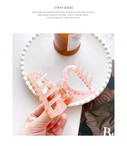 Detailed shot of a pink acetate hair claw with heart handle and luxury amber texture