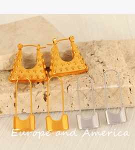 Detail of gold rivet hoop earrings and padlock pendants on natural stone background
