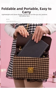 Portable black foldable travel makeup mirror being placed in a stylish lady handbag