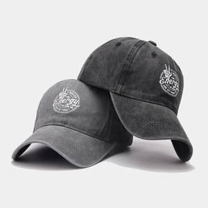 Détail de la texture en coton délavé et du slogan imprimé sur les casquettes noir et gris