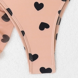 Détail du tissu de maillot de bain rose avec motifs de cœurs noirs et bordure soignée