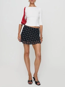 Close-up of a women's mini skirt featuring a classic black and white polka dot pattern