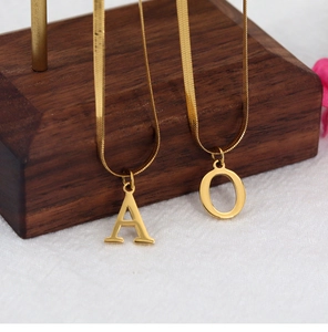 Detailed close-up of golden flat snake chain necklaces featuring letter A and O pendants