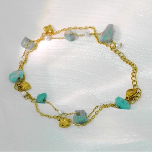 Detail of double-layer gold chain with turquoise stones, pearls and heart charms