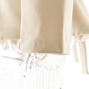 Close-up of beige knitted fabric texture showing premium woven material quality on sleeve