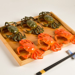 Realistic PVC crab food models in orange and green displayed on a bamboo tray