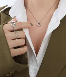 Detail of minimalist silver necklace and rings styled on professional business attire