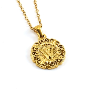 Detailed view of golden round pendant necklace featuring embossed letter W on white background
