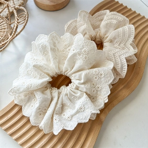 Gros plan de chouchous à broderie florale en dentelle sur un plateau en bois