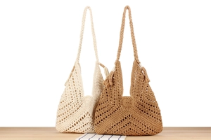 Detail of hollow woven shoulder bags in beige and brown with bohemian fringe tassels