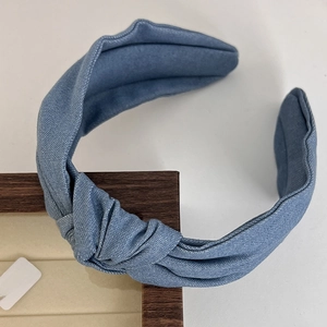 Detail of blue denim fabric headband featuring a vintage knotted design on a wooden frame