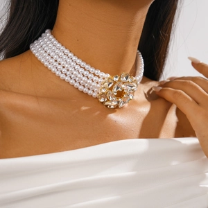 Macro detail of multi-strand faux pearl choker featuring a crystal floral pendant