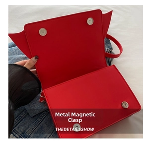Detail of red demon horn handbag featuring shiny finish and silver magnetic snap closure