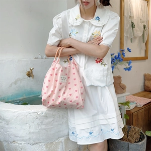 Detailed close-up of pink heart pattern tote bag with woven label on canvas fabric