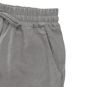 Detail of grey linen trousers featuring elastic waistband, drawstring and side pocket