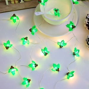 Christmas holly leaf LED string lights wrapped around a white ceramic cup and saucer