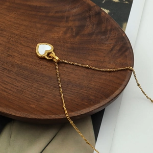 Macro detail of a 18K gold plated heart necklace with white shell inlay on wood