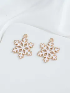Detailed macro of white enamel snowflake charms with gold metal base for DIY jewelry making