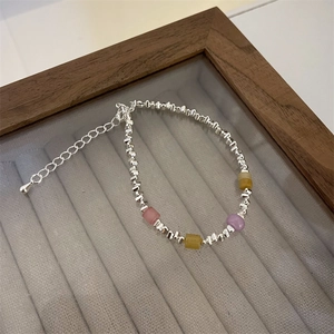 Detail of silver beaded heart bracelet with colorful natural stones on velvet display