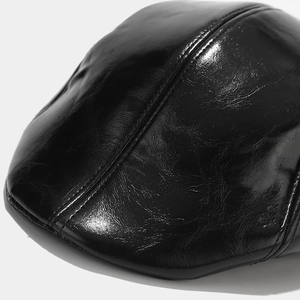 Detailed macro view of the glossy black faux leather texture and precise stitching of the cap