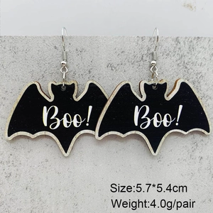 Detail of bat-shaped Halloween earrings featuring Boo text and metal hooks on marble