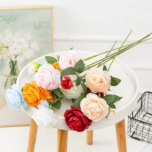 Detailed close-up of colorful artificial peony bouquet displayed on a small white table