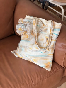Artistic marble pattern canvas tote bag with matching scrunchie on leather sofa