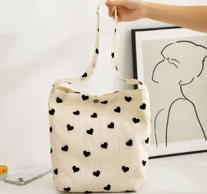 Detail der cremefarbenen Canvas-Tasche mit schwarzen Herzmustern und Knopfverschluss