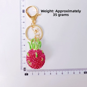 Creative dragon fruit keychain with pink rhinestones and gold clasp showing size dimensions