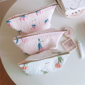 Détail de trois trousses à maquillage tulipe aux textures matelassées et motifs cerise