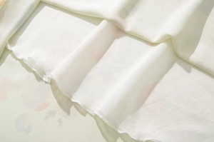 Gros plan du tissu blanc à volants montrant la texture douce et l'ourlet de la robe
