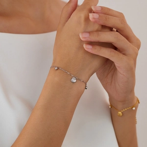 Detailansicht von Gold- und Silberarmbändern mit Muschelanhängern und Zirkon auf Model