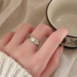 Close-up of enamel red rose and white daisy patterns on a silver flower ring
