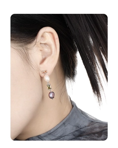 On-model shot of asymmetric long drop earrings with baroque pearls and colorful gemstones