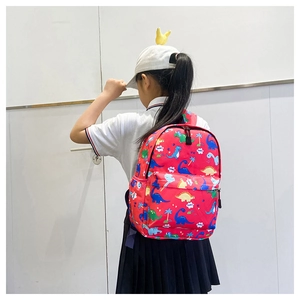 Detailed back view of a red dinosaur backpack with cartoon prints on a child model
