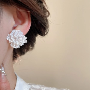 Primo piano di eleganti orecchini a fiore in pizzo bianco indossati da una modella