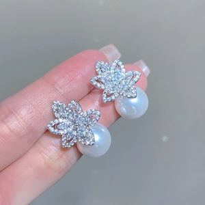 Detailed close-up of a flower-shaped zircon earring with a large round white pearl