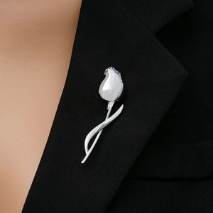 Close-up of a sleek silver tulip brooch pinned to a black blazer lapel for an elegant look