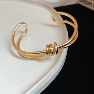 Macro shot of gold-plated twisted double-line knot bracelet on a white ceramic plate