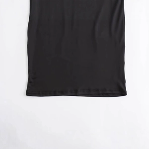 Close-up of the straight hemline and stitching of this black nylon asymmetric maxi dress