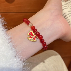 Gros plan détaillé d'un bracelet en perles d'agate rouge avec un charm poney doré