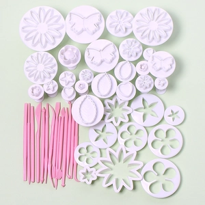 33-piece fondant cake tool set with white plungers and pink sculpting pens on green background