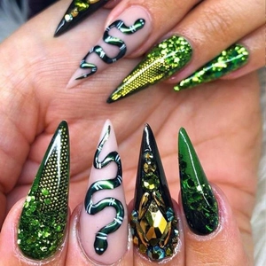 Long stiletto press-on nails with green snake patterns, gold rhinestones and glitter