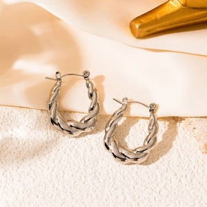 Detailed view of silver twisted rope hoop earrings on a textured satin background