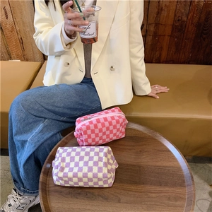 Detail of knitted checkerboard makeup bags with metal zippers in a warm cafe setting