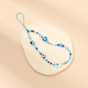 Detailed shot of blue beaded phone strap featuring evil eye and heart charms on props