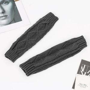 Close-up of grey knit arm warmers featuring diamond and cable patterns on a clean background