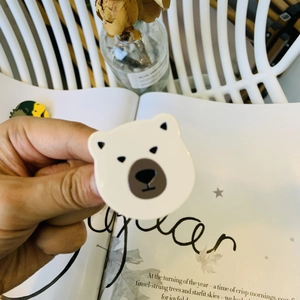 Cute white cartoon bear acetate hair clip with Y2K style held against a soft lifestyle background