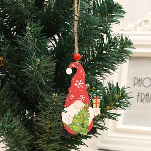 Detail eines hölzernen Weihnachtswichtels mit roter Mütze, hängend an einem Tannenzweig