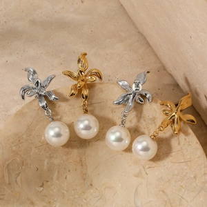 Floral pearl earrings in gold and silver finish set on minimalist stone background